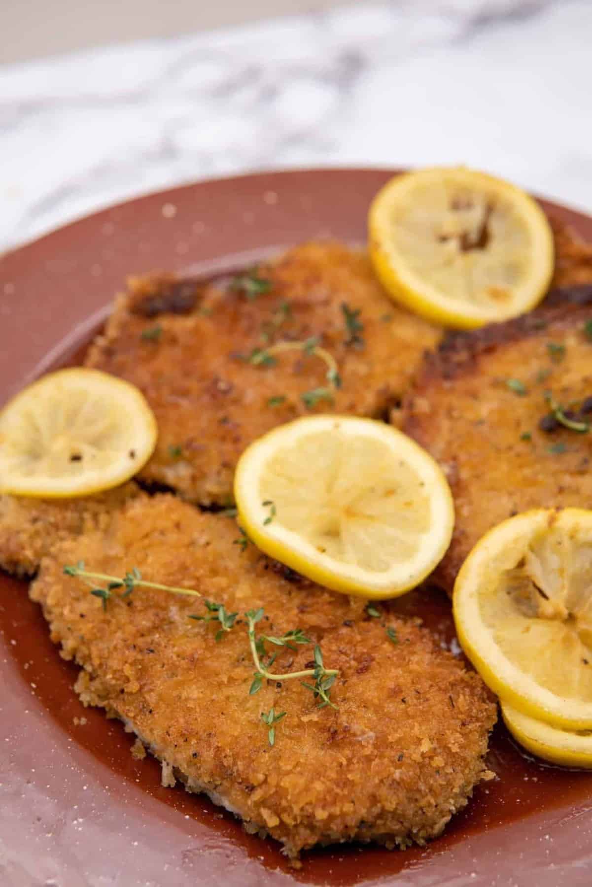 This Pork Schnitzel with Lemon Butter is made with pork chops, panko crumbs, garlic powder, onion powder, paprika, lemon and butter.