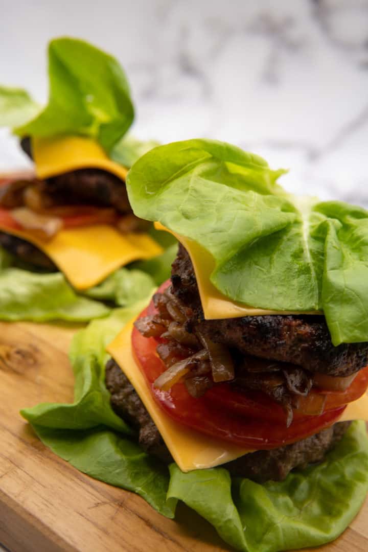 This Keto Double Lettuce Burger is made with caramelized onions, ground beef, onion powder, garlic powder, Worcestershire sauce, American cheese, butter lettuce, and tomato.