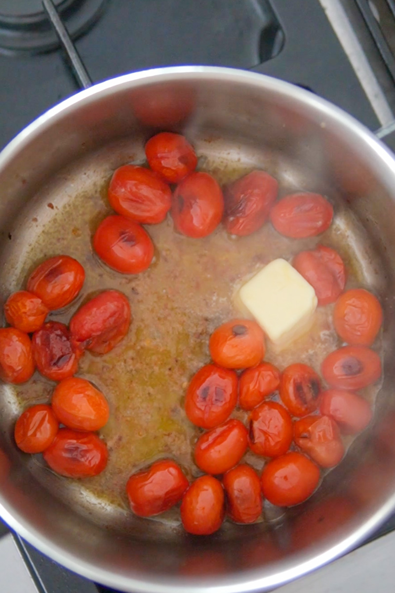 Meanwhile make the blistered tomatoes. Using a non-stick pot or saucepan, heat the oil over medium-high heat. Add the cherry tomatoes until starting to blister, about 3 to 4 minutes. Add butter until melted. Stir in the onions, white wine, and garlic and simmer for 5 minutes.