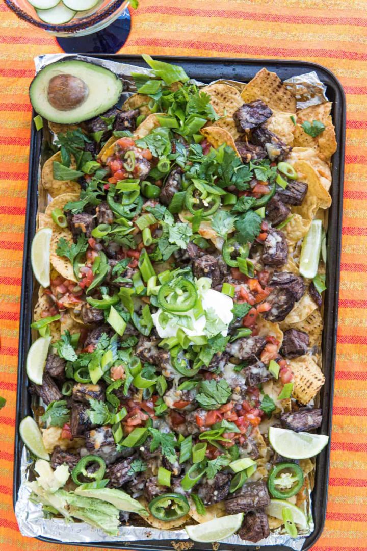 These Steak Nachos Recipe are made with carne asada marinated in soy sauce and lime juice, tortilla chips, jalapeños, and cheese.