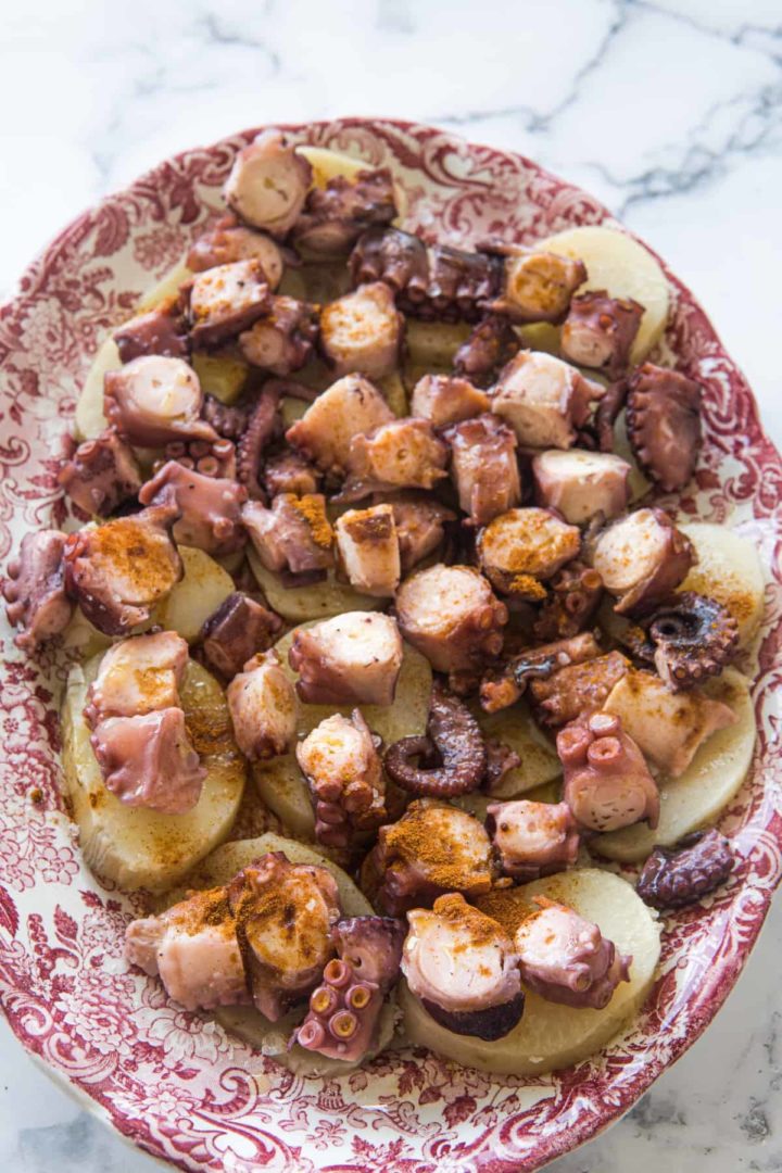 This Pulpo a la Gallega Recipe is made with boiled potatoes, cooked octopus, olive oil, pimentón, and salt and arranged on a large platter.