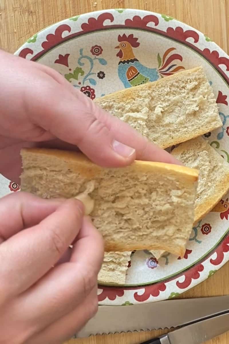 While the toast is still hot, rub each slice of bread with a garlic clove. Spoon the grated tomato pulp on each piece of toast and top with jamón serrano.