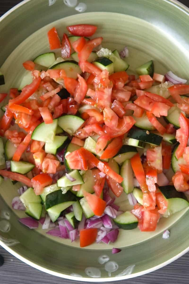 In a large bowl, combine the cherry tomatoes, cucumber, avocado, and red onion.