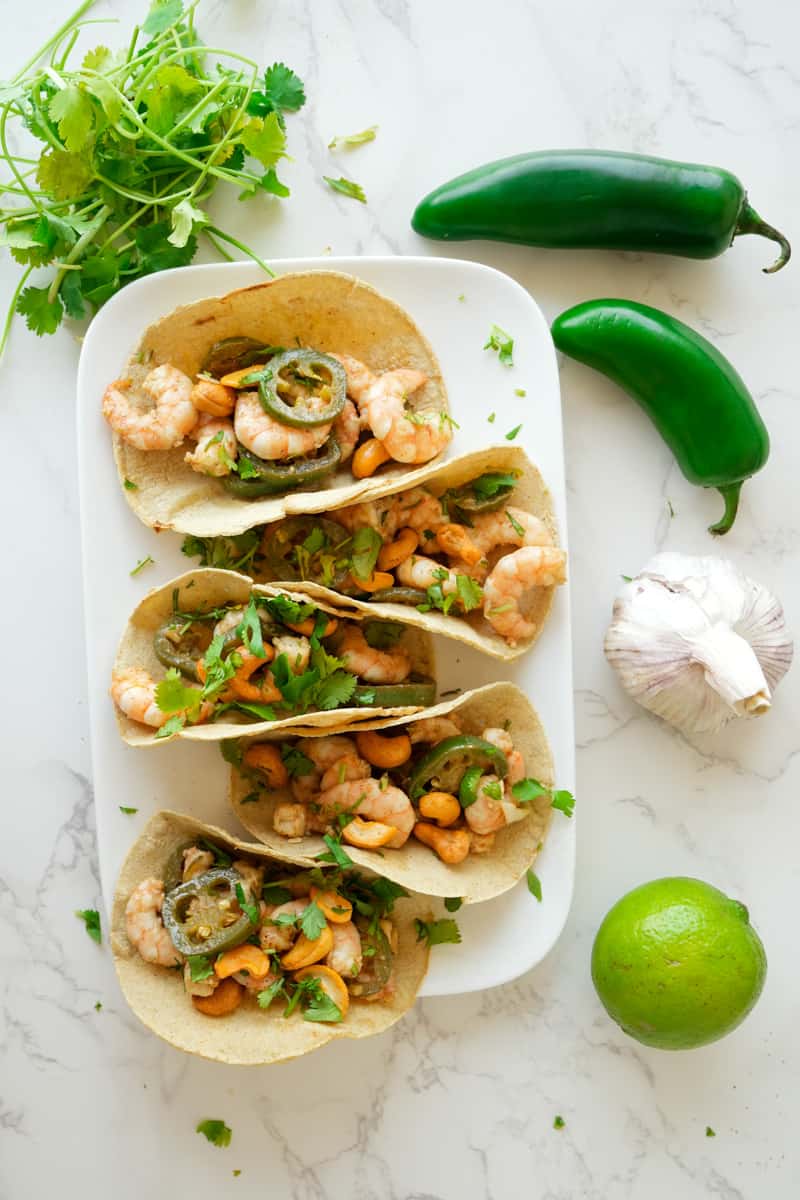 Serve serve the shrimp on warm tortillas. Garnish with cilantro and crushed cashews. Enjoy these Honey Lime Shrimp Tacos.