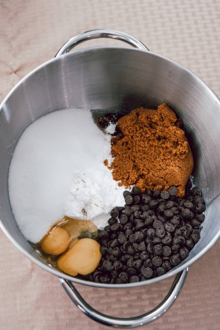 Preheat oven to 350 °F. In a large bowl, mix the butter, white sugar, and brown sugar until smooth. Beat in the eggs one at a time, then stir in the vanilla. Pour in baking soda into the batter along with salt. Stir in flour, chocolate chips, and nuts. 