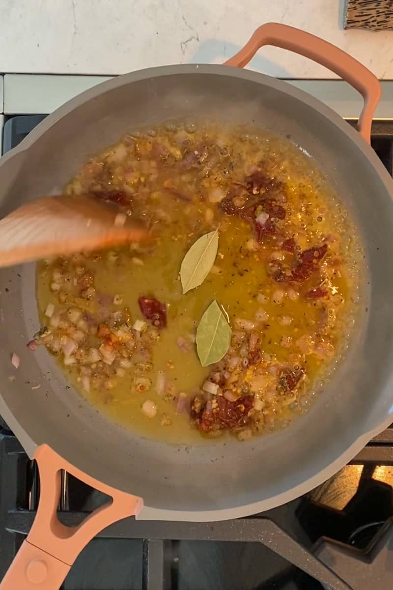 Add the orange juice, beans, bay leaves, ¼ cup of water and salt and pepper as needed. 