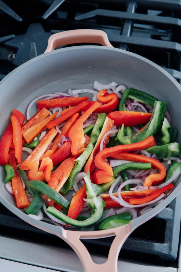 Heat a large cast iron over medium-high heat for 3 minutes. Once hot, add a bit olive oil. Sauté the onions until soft, about 4 minutes. Add the bell peppers and keep stirring until soft, about 5 minutes. Place the onions and peppers on a separate plate.  