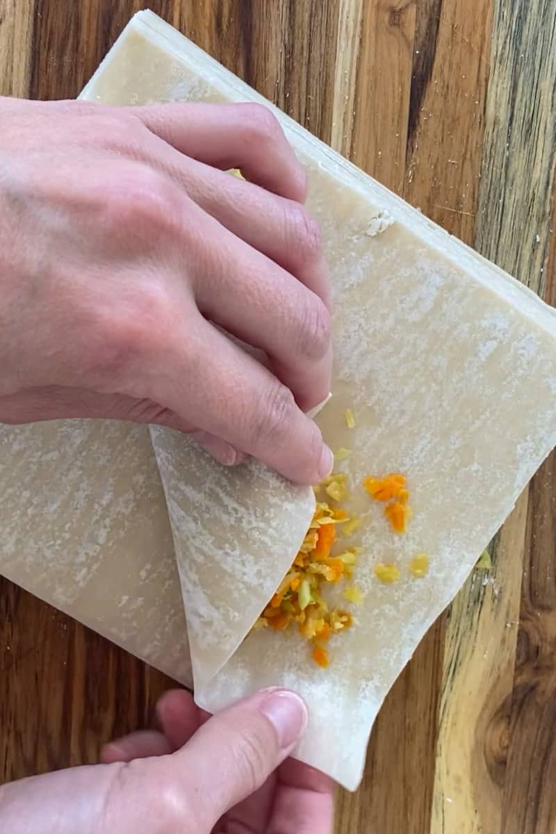 Assemble the egg rolls. Add two tablespoons of the cabbage mixture on a sheet of egg roll wrapper. Fold bottom corner over filling and then fold the side corners. Bruch the top corner with water and roll the wrap tightly to enclose the filling. Brush the entire egg roll with vegetable oil.