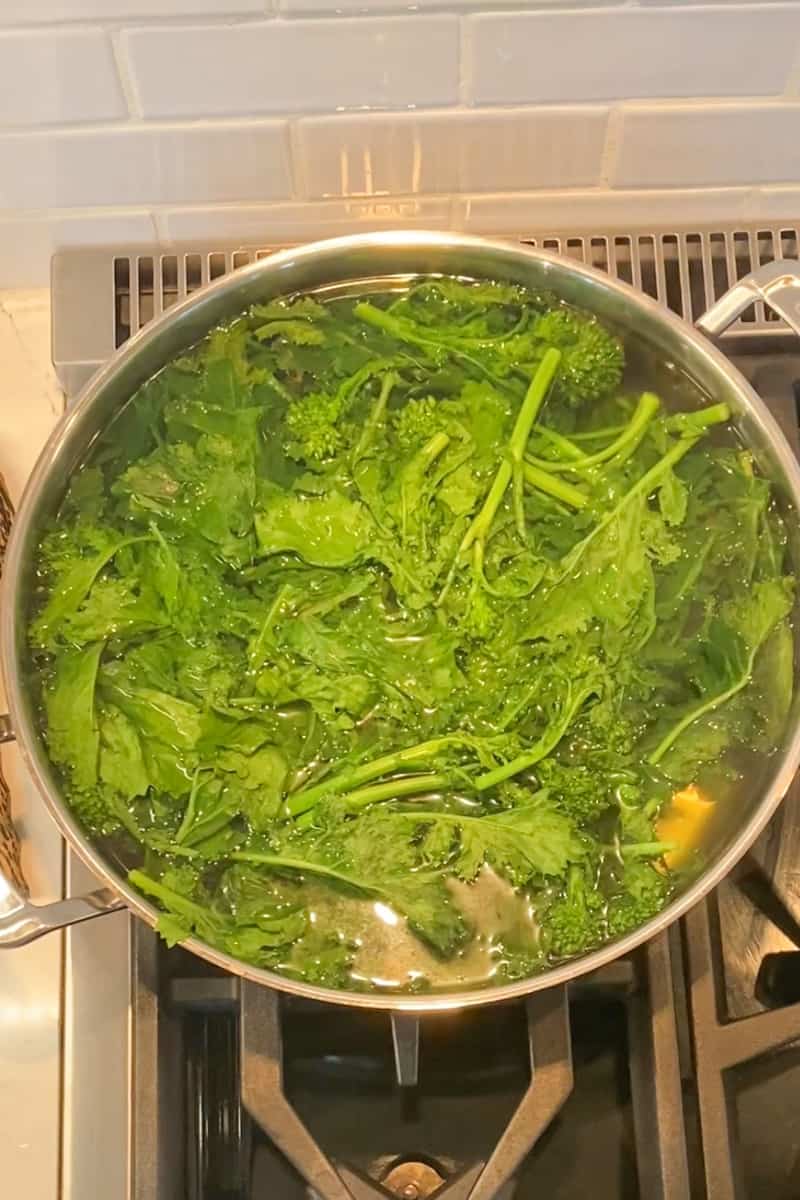 Start by blanching the broccoli rabe in a deep pan of boiling water. Put the broccoli rabe in for 2 minutes and take it out. When you are done, use tongs to take the broccoli rabe out and set aside. Do not strain the water as we will be cooking the pasta inside the same pot of water!