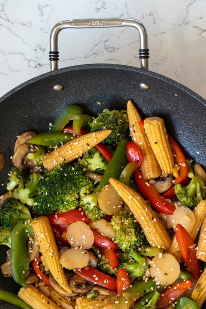 This baby corn stir fry is made with mushrooms, broccoli, bell peppers, baby corn, water chestnuts, soy sauce, and sesame seeds.