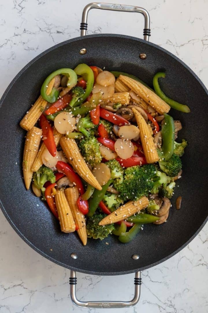 This baby corn stir fry is made with mushrooms, broccoli, bell peppers, baby corn, water chestnuts, soy sauce, and sesame seeds.