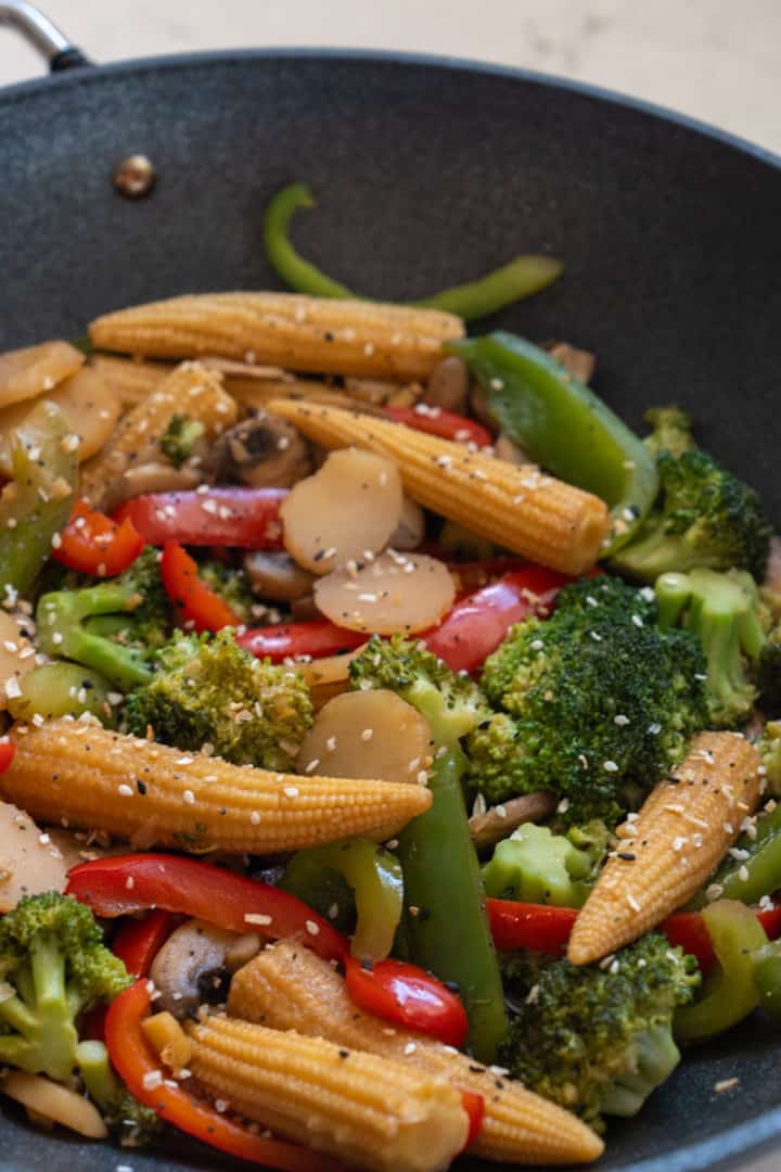 This baby corn stir fry is made with mushrooms, broccoli, bell peppers, baby corn, water chestnuts, soy sauce, and sesame seeds.