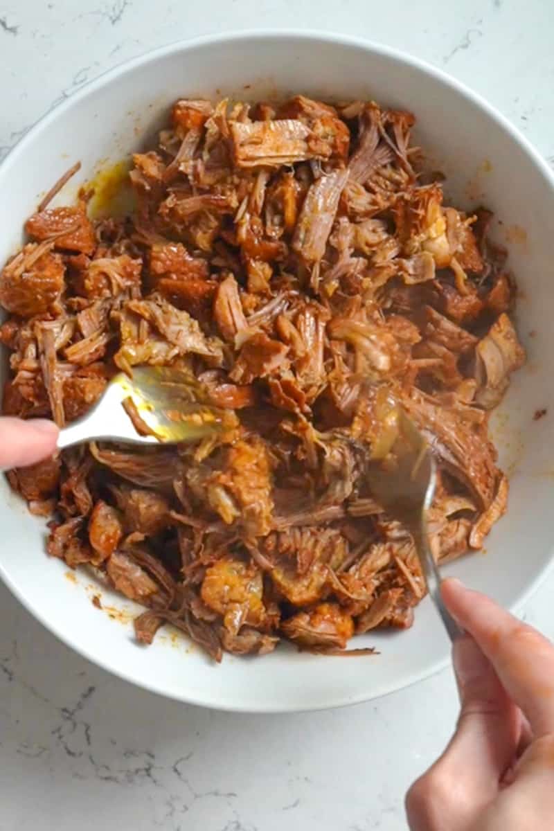 With a slotted spoon, place the pork into a bowl or baking dish. Shred the pork with 2 forks. It should be extremely soft at this point. Pour the sauce back into it. 