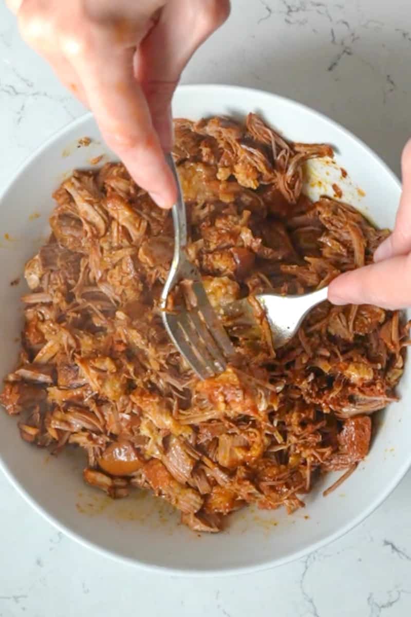 Shred the pork with 2 forks. It should be extremely soft at this point. Pour the sauce back into it. 