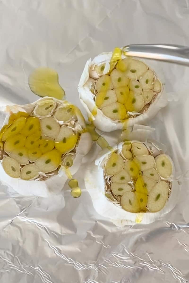 Preheat the oven to 400 °F. Cut the top part of the heads of garlic and drizzle olive oil on top of the cut portion. Wrap the entire garlic heads, individually, with aluminum foil. Roast in the oven for 1 ½ hours.