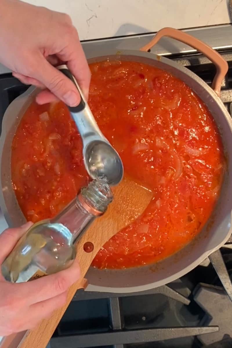 Pour in the tomatoes into the onions. Stir well and add the olive oil, Calabrian chilies, vodka and butter. Stir and bring to a boil. Simmer on medium heat for 20 minutes.
