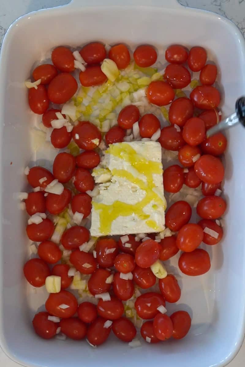 Preheat oven to 400°F. In a large ovenproof making dish, place the feta in the center of the dish and add the tomatoes, shallot garlic, and olive oil around. Season with salt and red pepper flakes.