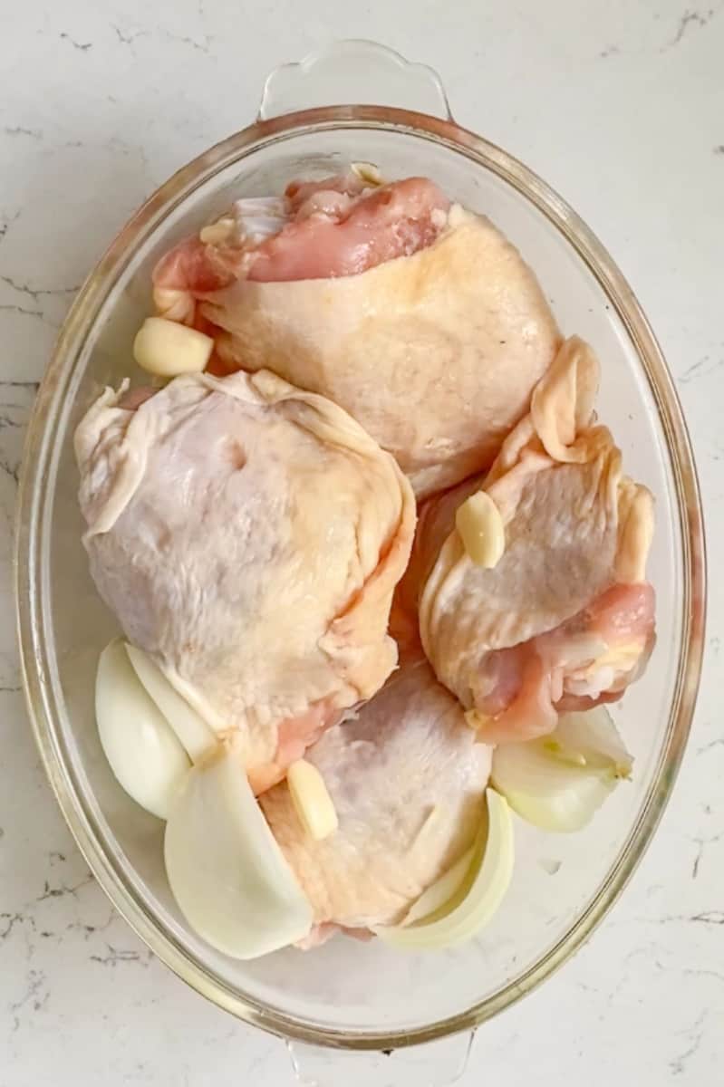 Preheat oven to 400°F. Add the chicken, onion, lemons slices, and garlic in a oven safe bowl. 