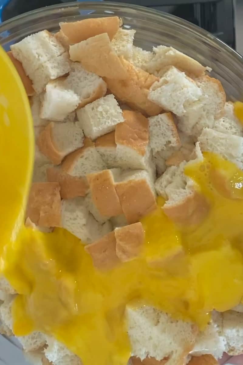 Add the bite sized Kaiser roll bread into a large bowl. Add the beaten eggs, milk, and parmesan cheese. Mix with your hands and let it soak for 30 minutes.