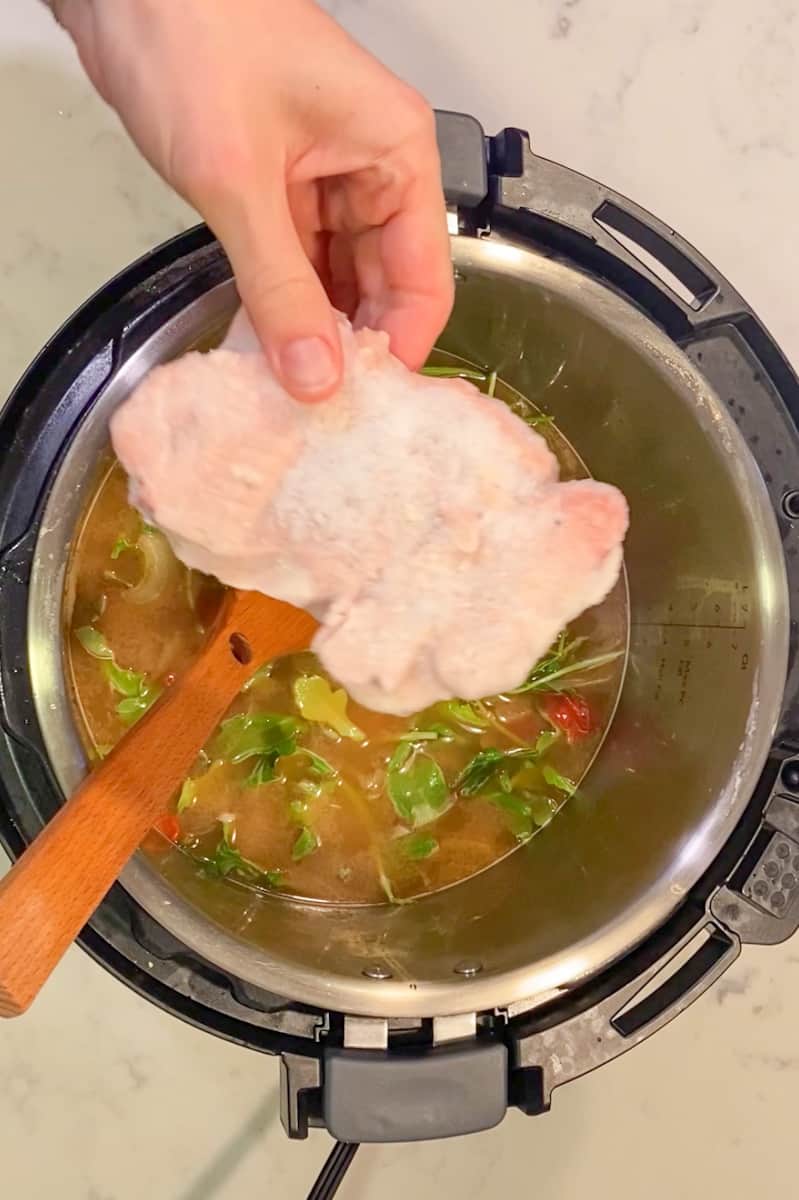 Pour in the diced tomatoes, chicken broth, spinach, and frozen chicken breasts.