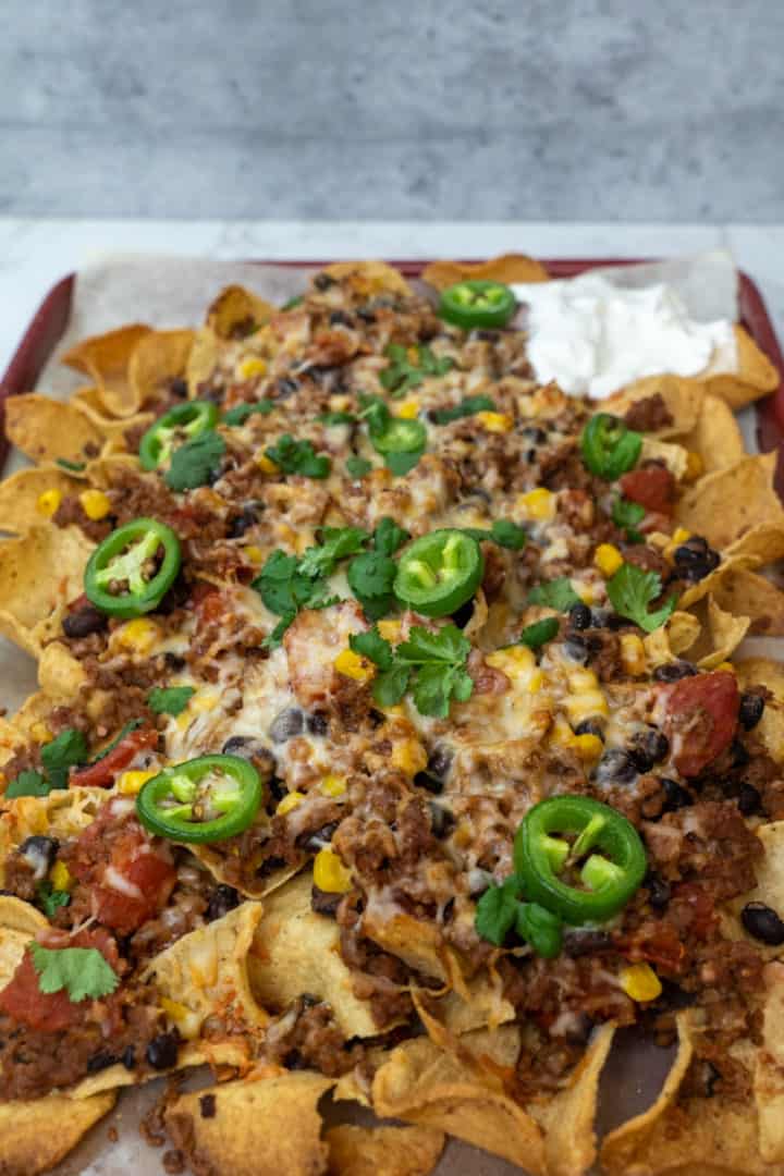 These Vegetarian Nachos with Beyond Beef are made with plant based ground beef, corn, tomatoes, black beans, Monterrey Jack cheese and baked on a bed of tortilla chips.