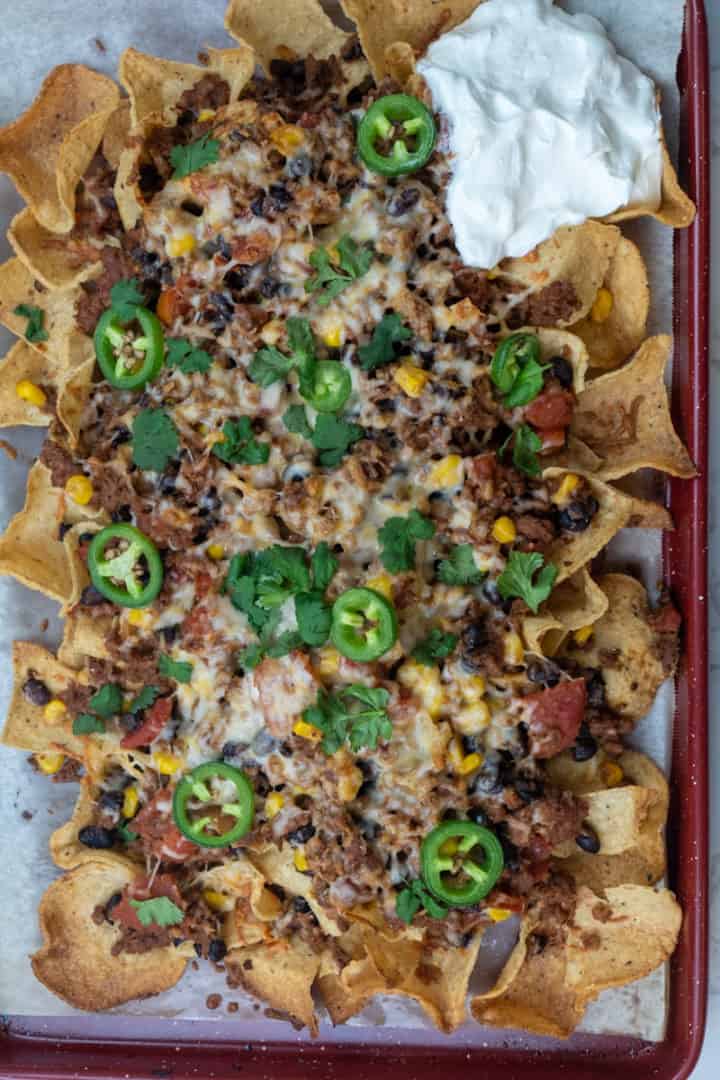 These Vegetarian Nachos with Beyond Beef are made with plant based ground beef, corn, tomatoes, black beans, Monterrey Jack cheese and baked on a bed of tortilla chips.