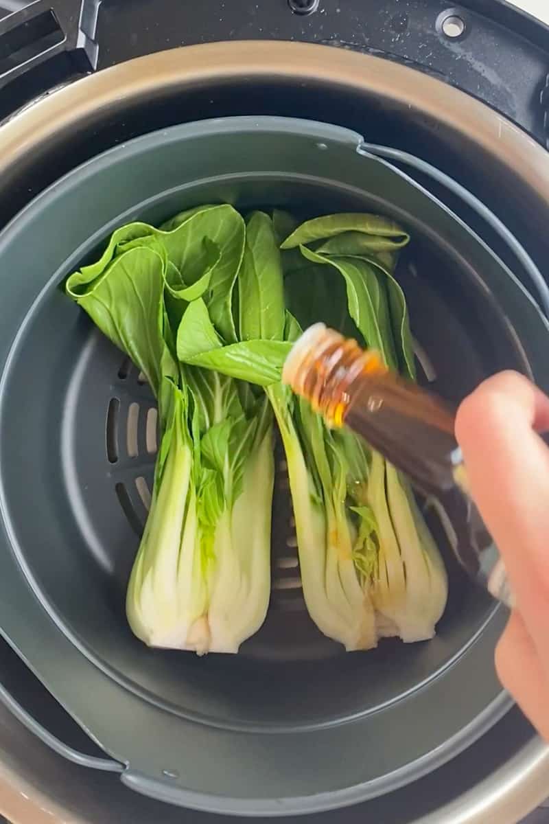 Rinse the bok choy and pat dry. Cut the baby bok choy lengthwise. Spray the inside of the air fryer with non-stick cooking spray. Place the baby bok choy cut side up. Drizzle sesame oil and sprinkle garlic powder on the bok choy.