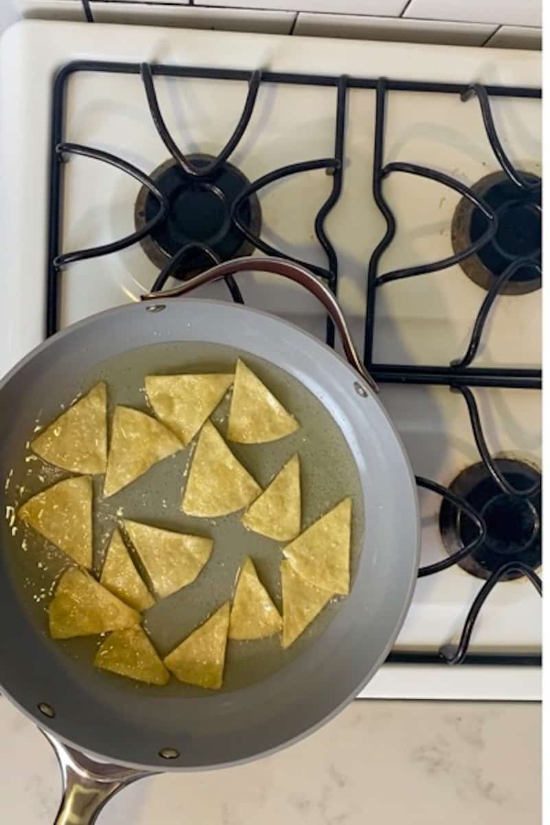  Add the pieces of tortilla into the pan and fry until golden.