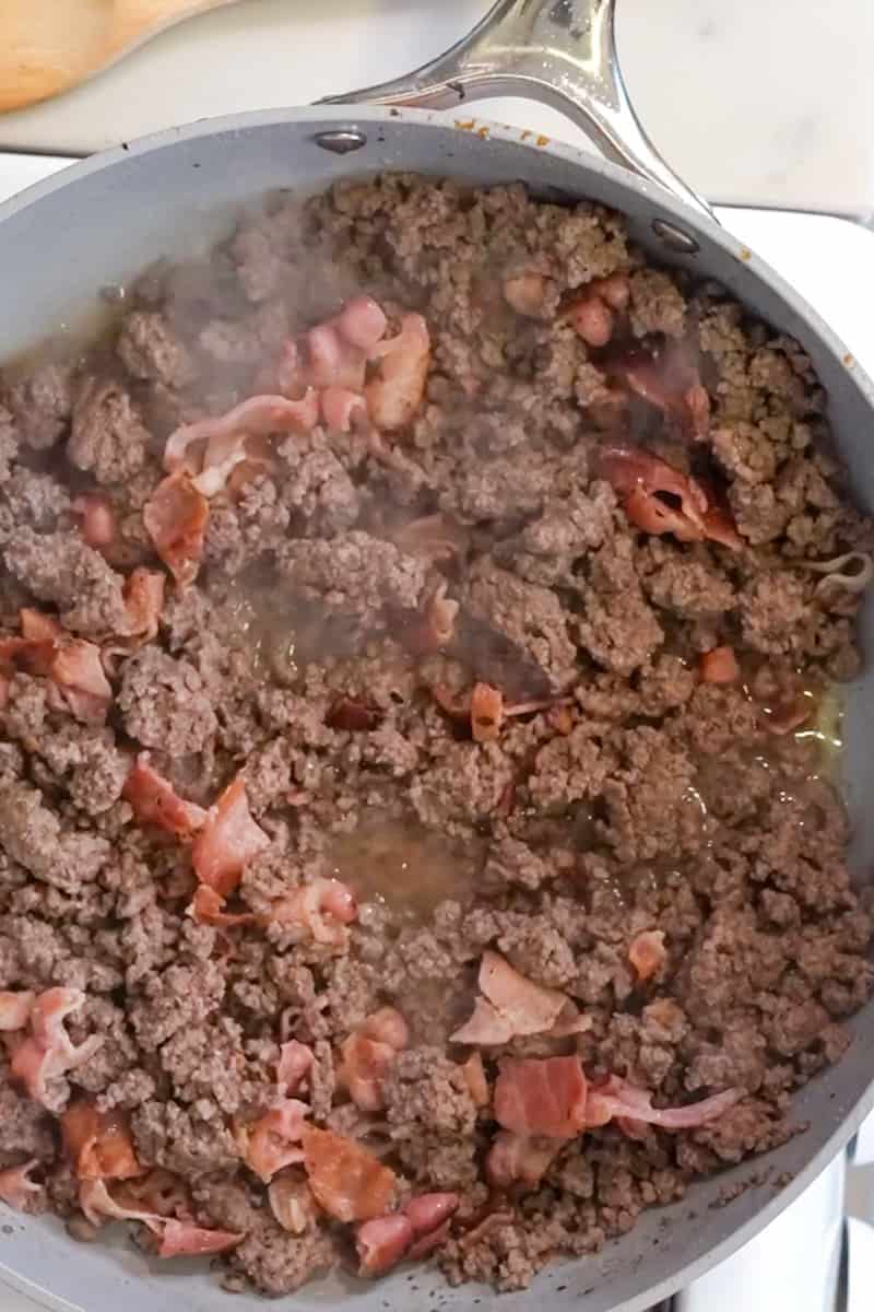 In the same skillet, cook the ground beef for 6 minutes, breaking the meat into smaller pieces and season with onion power and garlic powder. Chop the bacon and throw back into the skillet with the meat. Wait until the moisture evaporates and allow the meat to brown. Make sure there is no signs of pink!