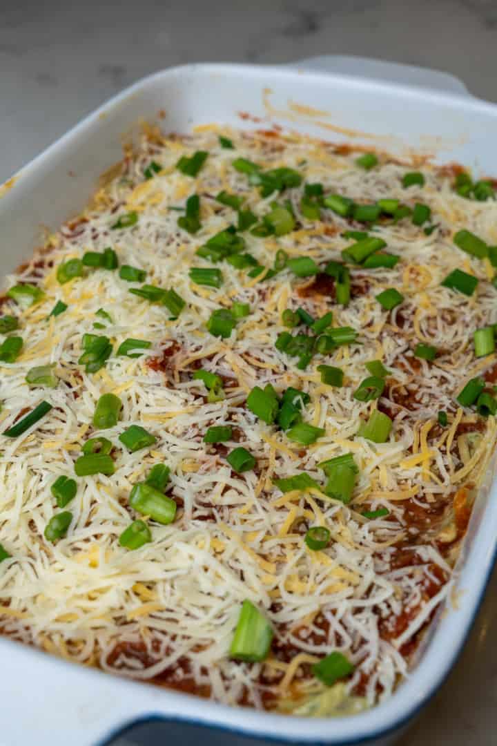 This 7 Layer Dip with Cream Cheese (Gluten Free and Keto) is made with salsa, refried beans, cream cheese, sour cream, taco seasoning, guacamole, shredded cheese and green onion.
