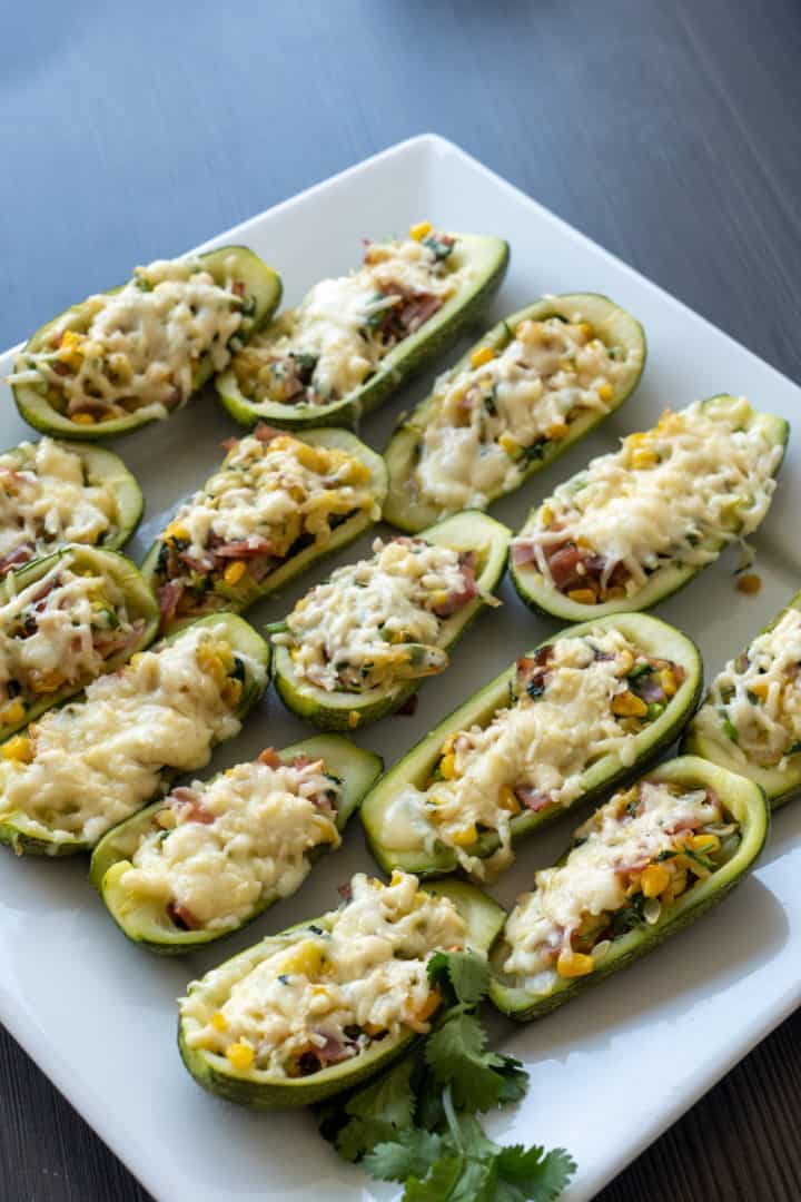 These Zucchini Boats Keto are made with bacon, corn, red onion, garlic, cilantro, and filled into zucchinis and baked with melted cheese on top.