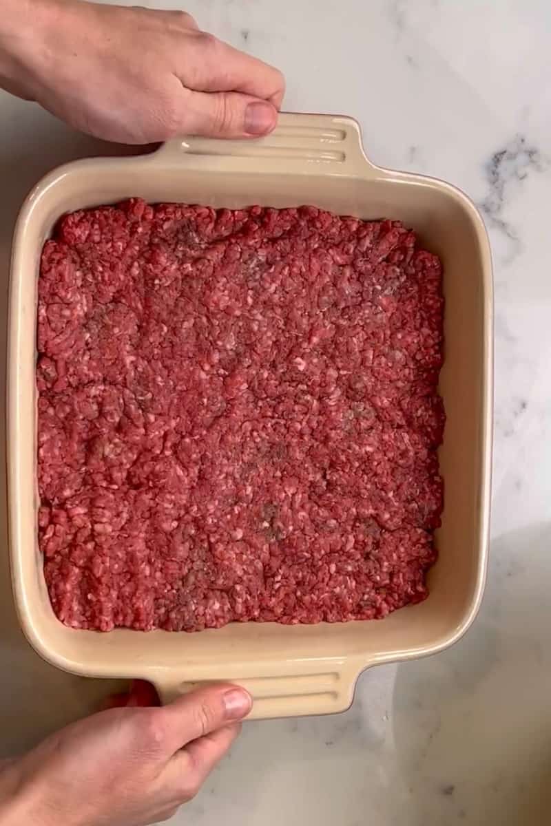 Preheat the oven to 350°F. Combine the beef, salt, pepper and garlic powder in a 9x9 inch baking dish and press into a flat, even layer. Bake for 20 minutes and drain the liquid after.