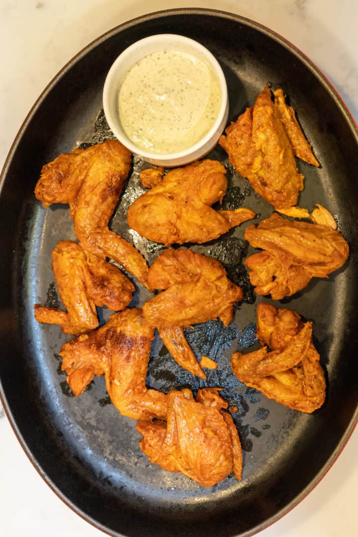 These Truff Hot Sauce Wings are made with chicken wings, baking powder, paprika, Truff hot sauce, butter, and served with ranch on the side.