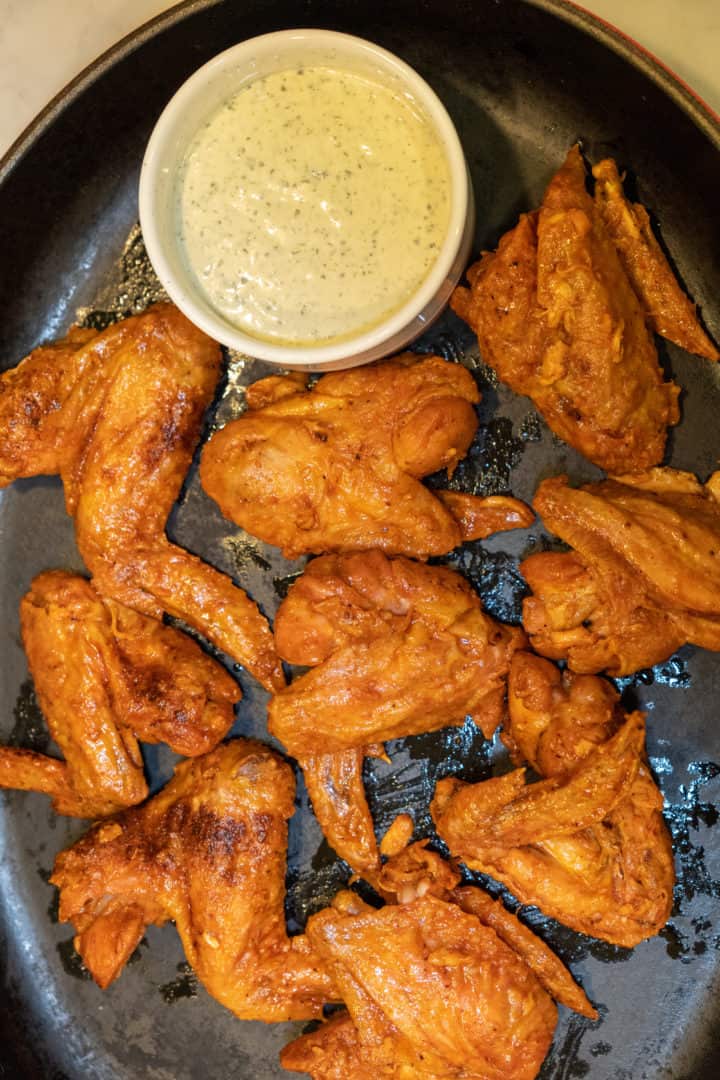 These Truff Hot Sauce Wings are made with chicken wings, baking powder, paprika, Truff hot sauce, butter, and served with ranch on the side.