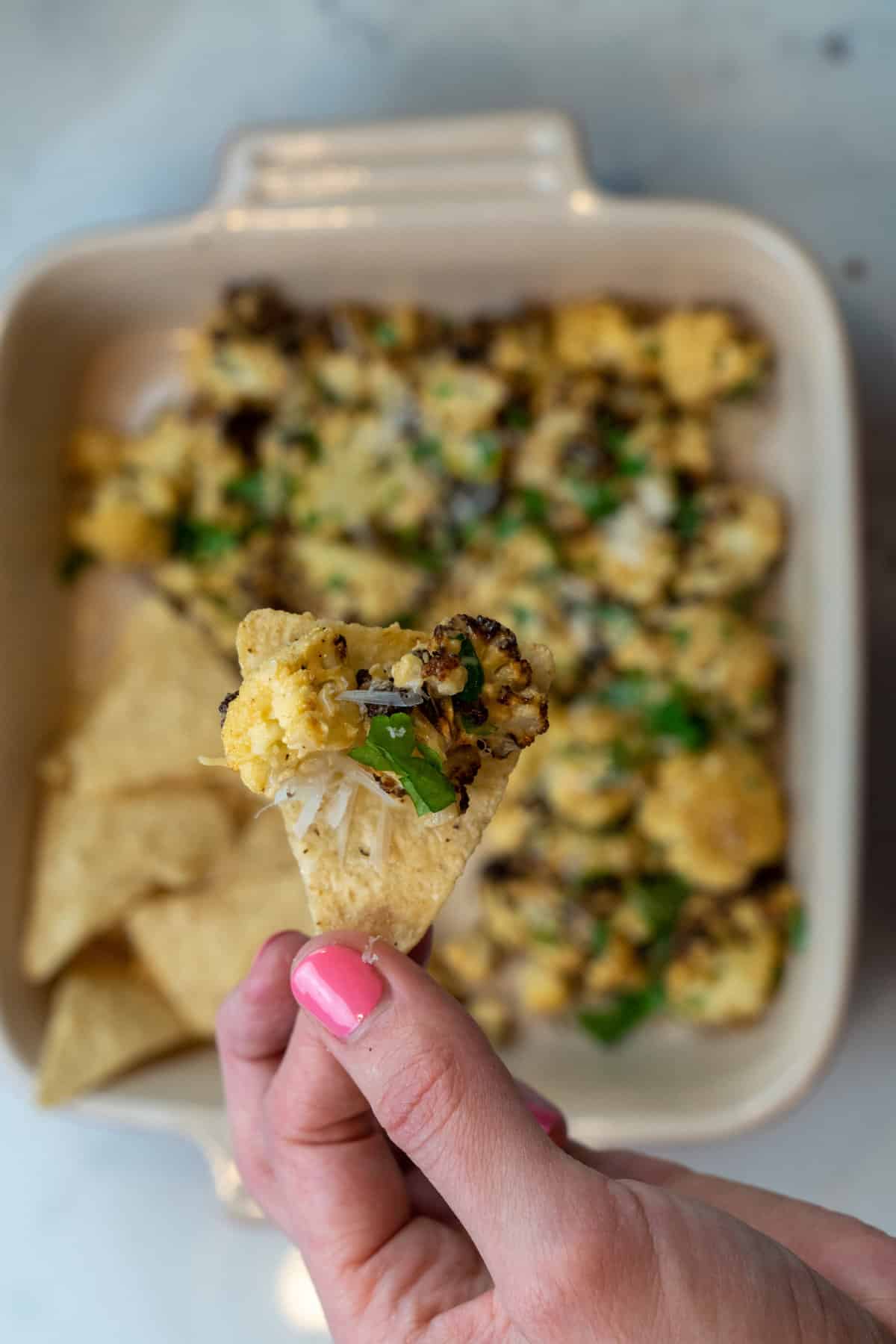 Plate the Mexican Cauliflower Elote (Keto and Gluten Free) and top with the extra cheese and cilantro. Serve with tortilla chips.