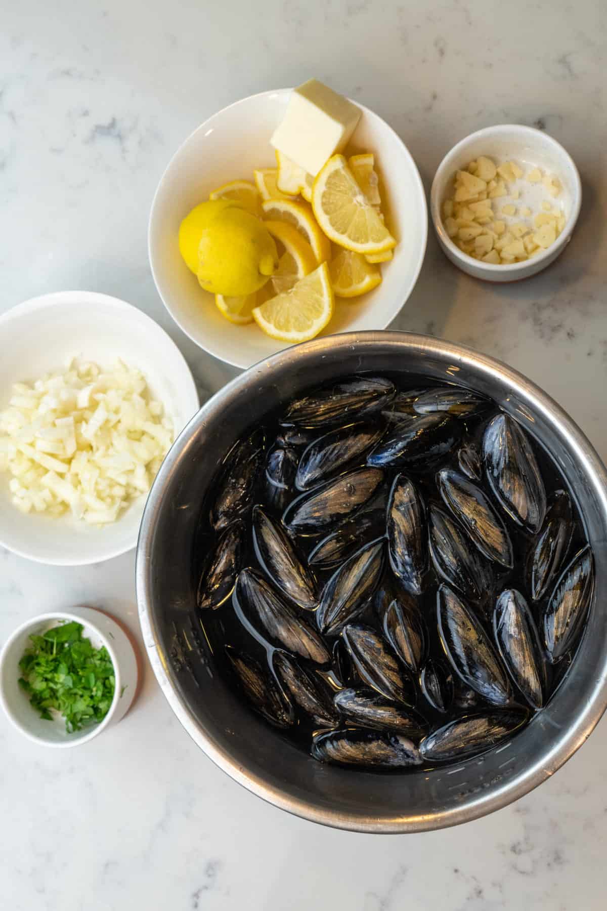 This Steamed Mussels Recipe with White Wine Cream Sauce is made with mussels, butter, garlic cloves, onion, wine, cream, lemon, and parsley.