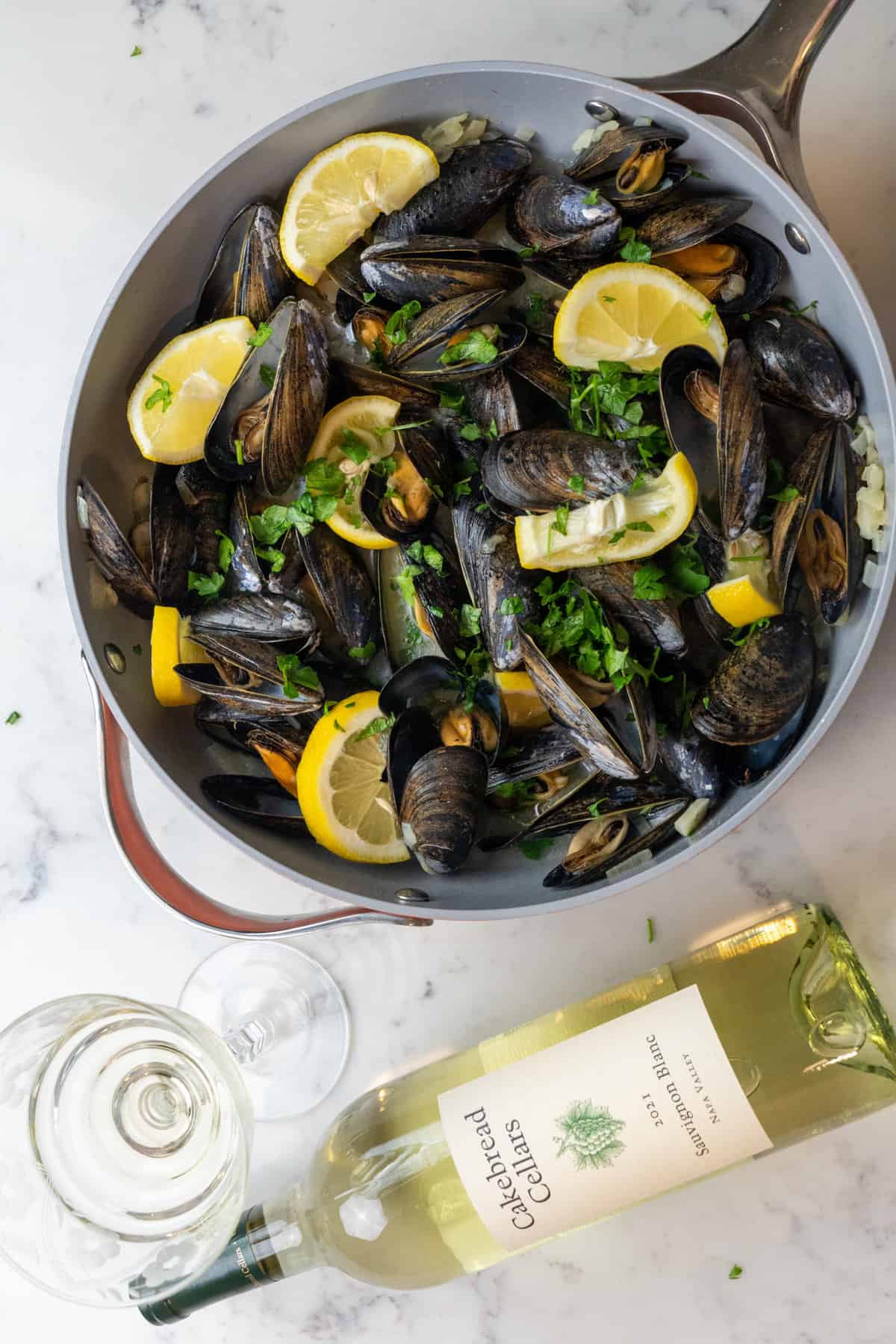 These mussels in White Wine Cream Sauce is made with mussels, butter, garlic cloves, onion, white wine, heavy cream, lemon, and parsley.