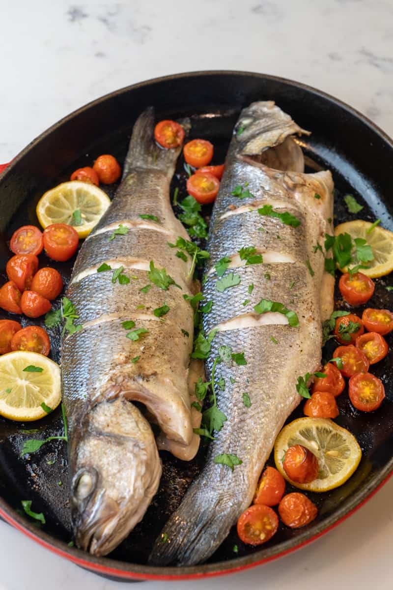 This Whole Roasted Branzino Recipe is made with whole branzino, olive oil, cherry tomatoes, lemon slices, butter, parsley and baked to perfection.