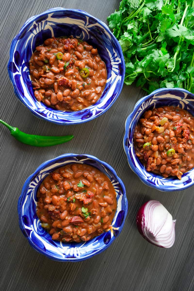 These Mexican Charro Beans Recipe (Frijoles Charros) are made with pinto beans, onion, garlic, diced tomatoes, cilantro and can be made in dutch oven or pressure cooker.
