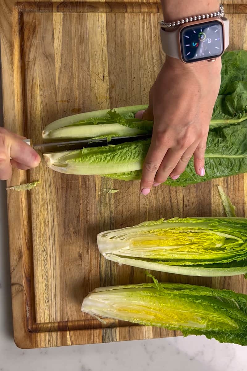 Preheat a gas or charcoal grill for direct, medium high heat grilling. Alternatively, you can use a grill pan on medium-high heat. Cut each romaine heart in half lengthwise and brush the cut side on each half lightly with olive oil.