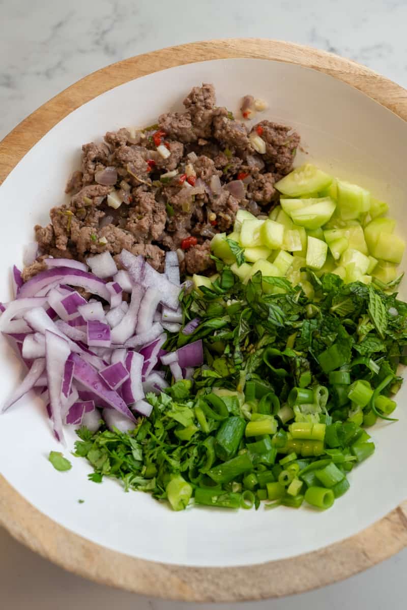 This Thai Lamb Larb Recipe is made by cooking ground lamb and tossing into a bowl of cucumber, scallions, cilantro, mint, and Thai basil.