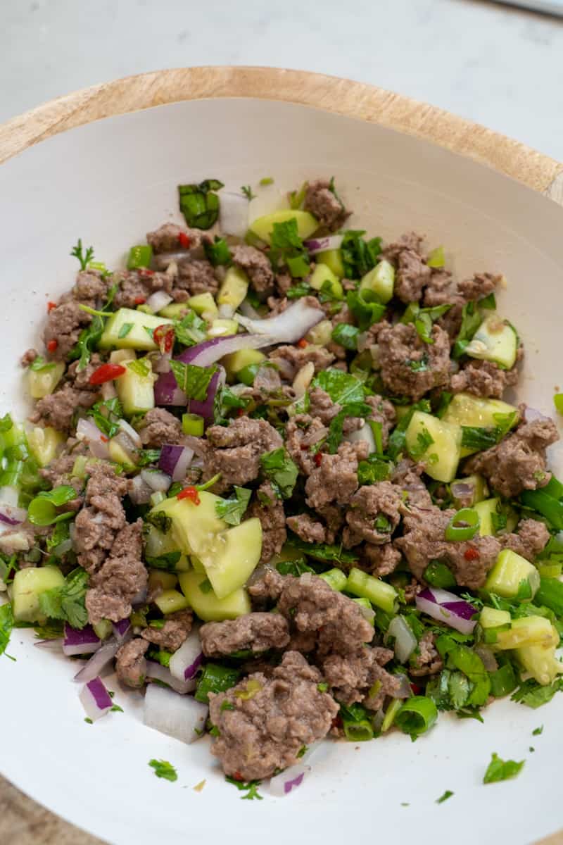  In a large bowl, add the ground lamb mixture, cucumber, scallions, cilantro leaves, mint, and Thai basil. Pour the fish sauce mixture over everything. Toss the salad to combine.