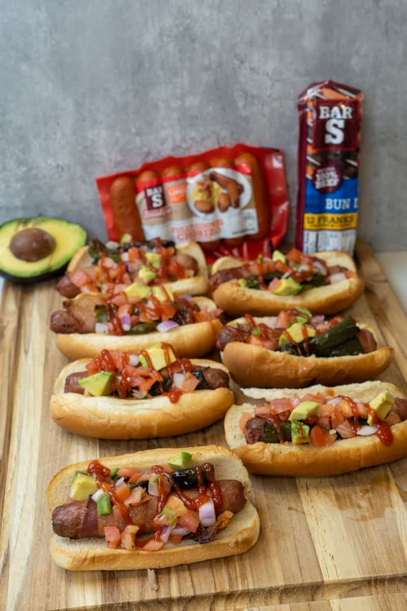 This Sonoran Hot Dog Recipe is made by wrapping each hot dog with bacon, baking them, and topping each hot dog with jalapeños and pico.