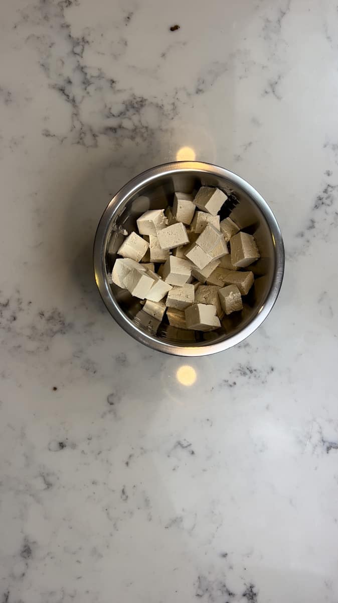 Cut the tofu into large chunks and add them to a bowl. Toss in the olive oil, hot sauce, garlic powder, paprika, and starch. Toss until the tofu is evenly coated.
