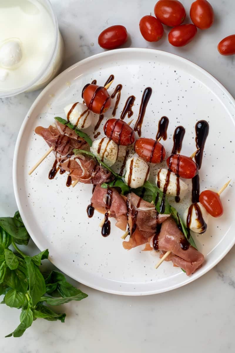 These Caprese Skewers with Prosciutto and made with tomatoes, mozzarella, basil and prosciutto and topped with balsamic glaze.