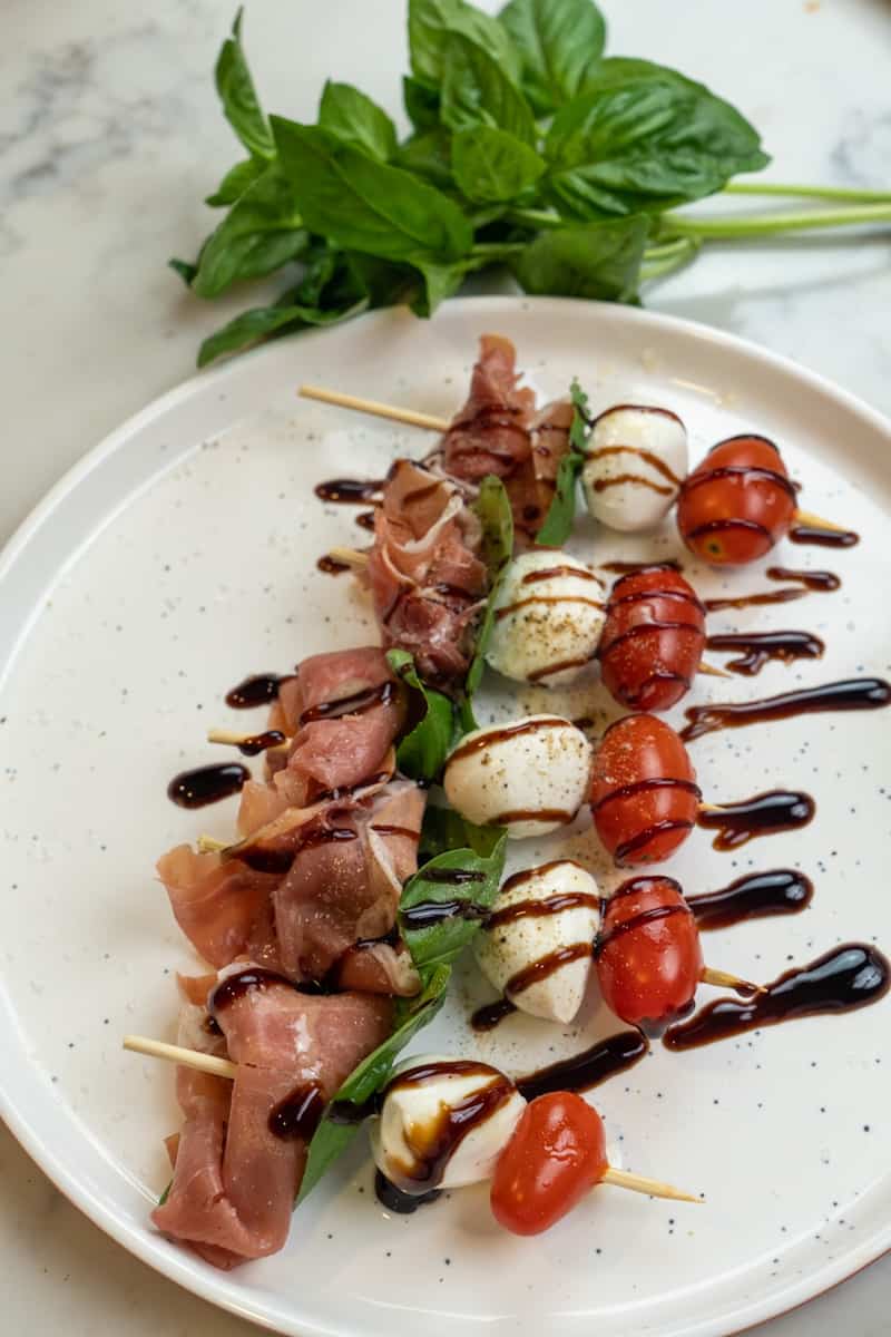 These Caprese Skewers with Prosciutto and made with tomatoes, mozzarella, basil and prosciutto and topped with balsamic glaze.