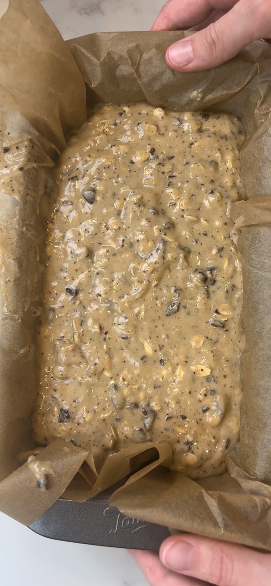 Pour the Banana Oat Chocolate Chip Bread batter into the loaf pan lined with parchment paper. 