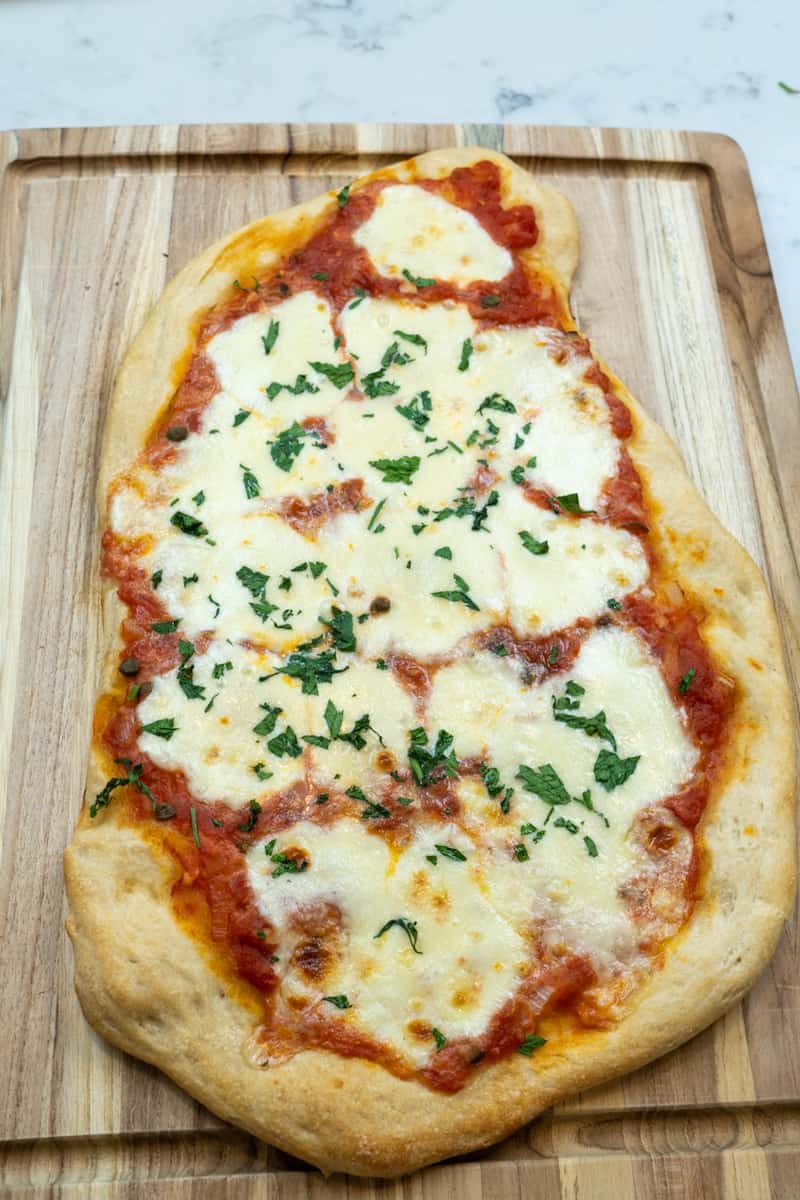 This Pizza Puttanesca is made with homemade puttanesca sauce and spread on store bought pizza dough, topped with mozzarella and baked for 20 minutes.