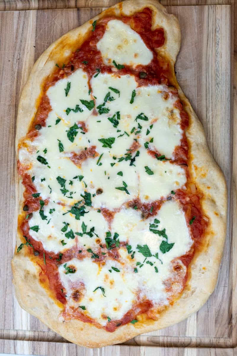 This Pizza Puttanesca is made with homemade puttanesca sauce and spread on store bought pizza dough, topped with mozzarella and baked for 20 minutes.