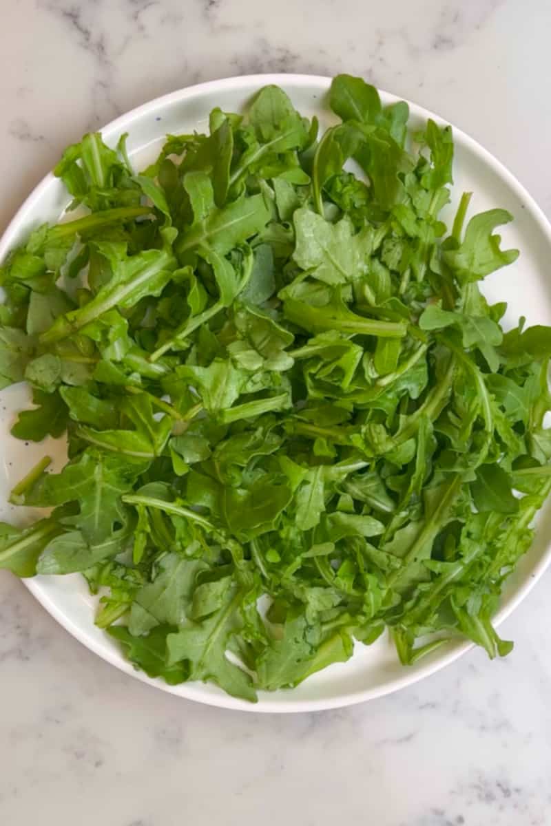 Place the arugula in a large plate or salad bowl.